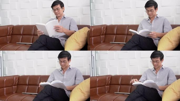 亚洲老人眼镜教授坐在椅子上阅读教科书与copyspace