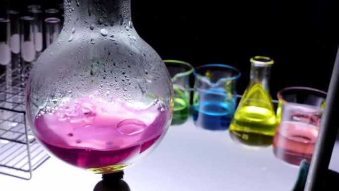 关闭酒精灯是用黑色背景的实验室玻璃器皿在烧瓶中沸腾的红色化学液体。实验室研究与开发