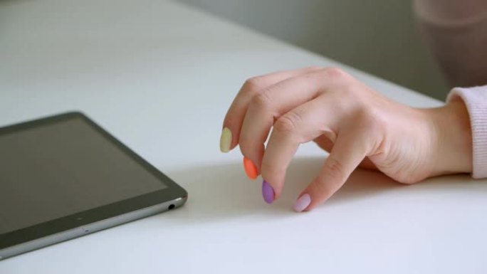 在办公室室内使用平板电脑拍摄美丽修指甲的女性手的特写镜头