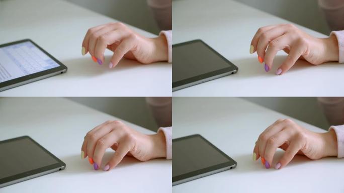 在办公室室内使用平板电脑拍摄美丽修指甲的女性手的特写镜头
