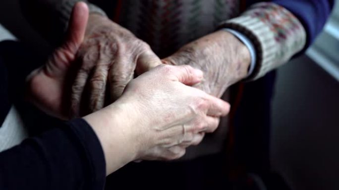 女托儿所照顾老年男子在医院的皱纹之手，妇女支持患有阿尔茨海默氏病的老人，对老年人的爱与关怀。老人在医