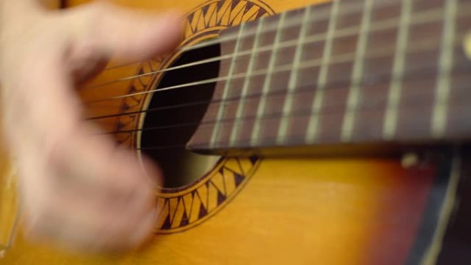 弹吉他，一个男人用手特写敲打琴弦。