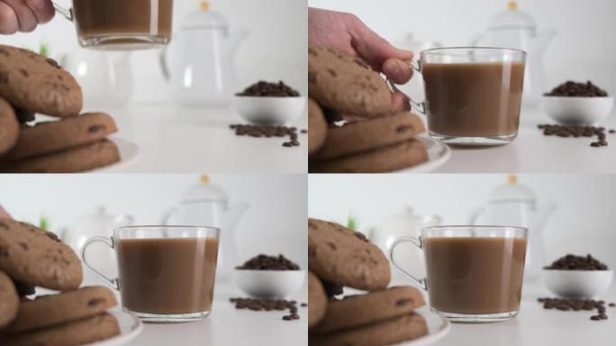 将玻璃咖啡杯放在装有巧克力饼干的白色桌子上。特写。