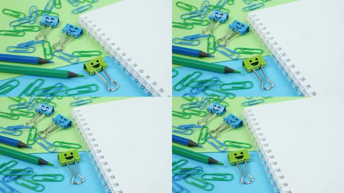 绿色和蓝色办公室纸夹、微笑活页夹和记事本上的铅笔