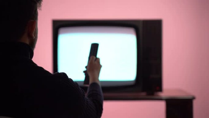 屏幕上有噪音干扰的老式复古电视。男性手持老式电视遥控器和换台。老式电视和广播，复古风格