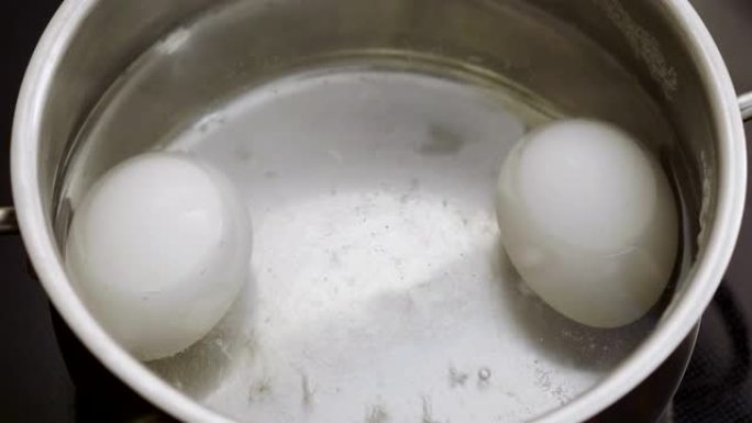 在一锅开水中特写两个白鸡蛋。4K