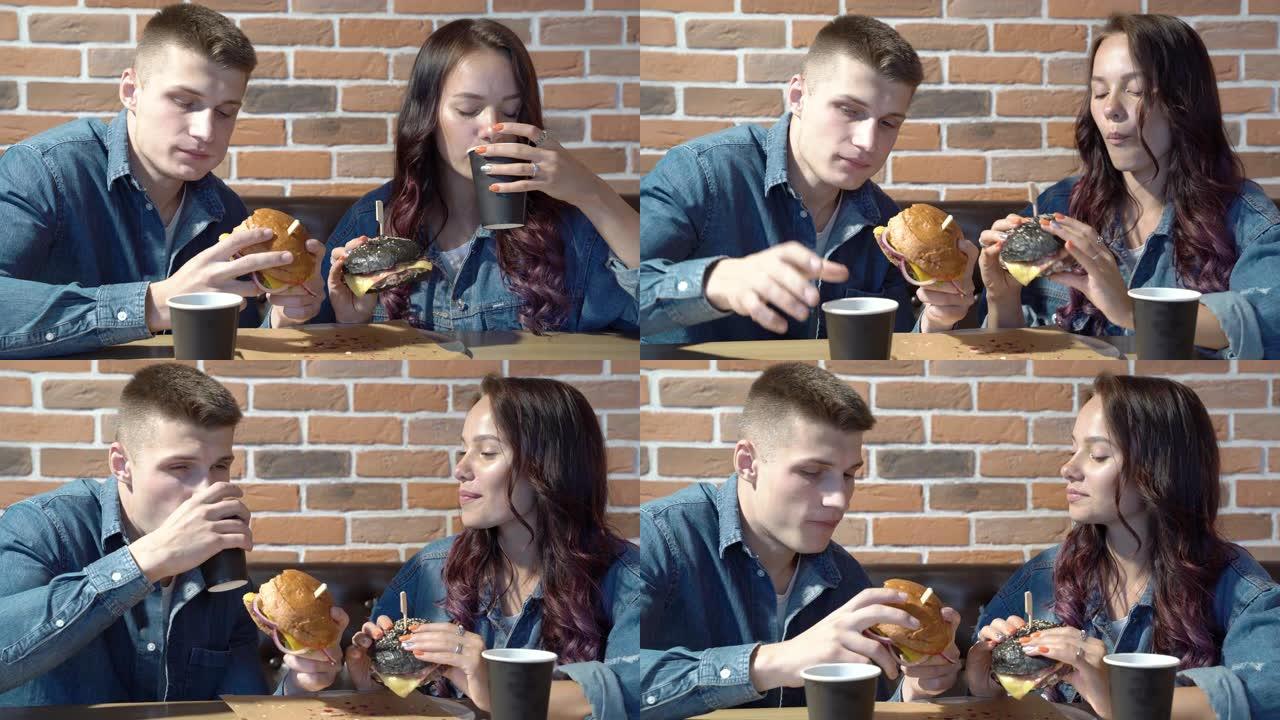 幸福的夫妇吃汉堡，一起在咖啡馆玩得开心。