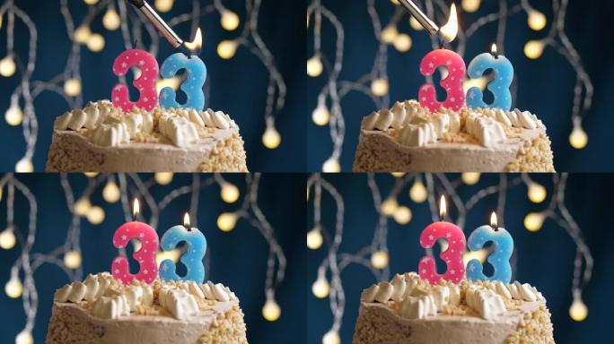 蓝色背景上有33号粉色蜡烛的生日蛋糕。蜡烛着火了。慢动作和特写视图