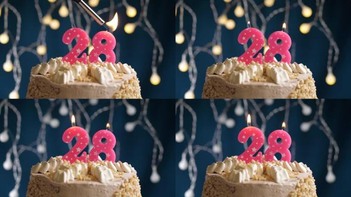 蓝色背景上有28号粉色蜡烛的生日蛋糕。蜡烛着火了。慢动作和特写视图