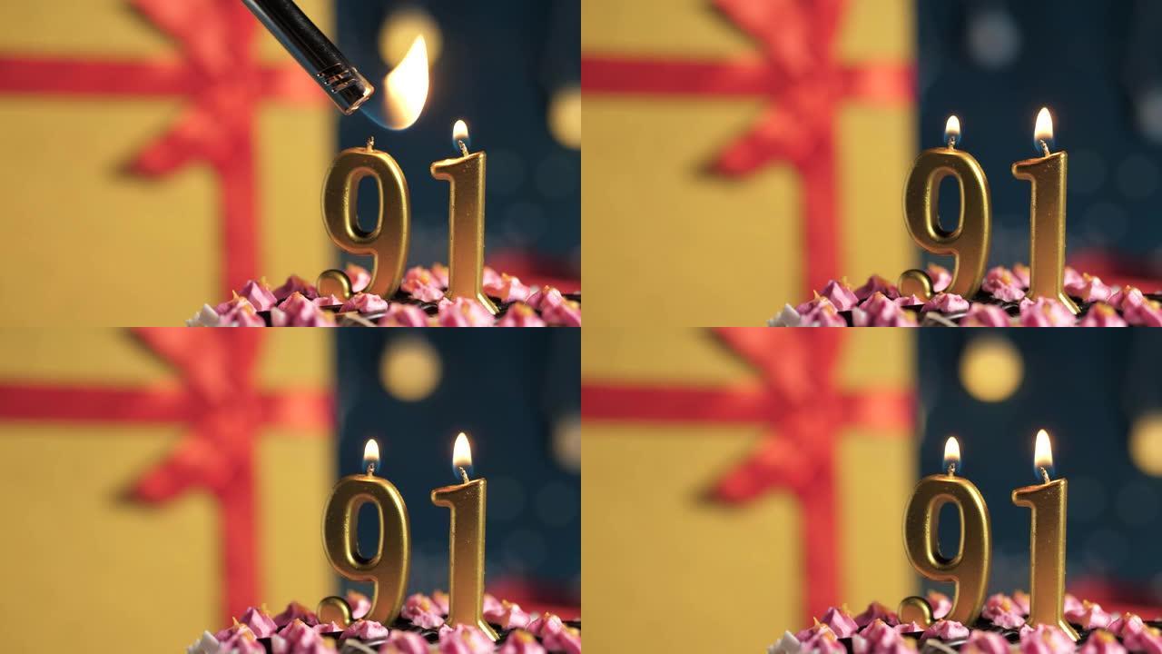 生日蛋糕编号91点灯燃烧的金色蜡烛，蓝色背景礼物黄色盒子用红丝带绑起来。特写和慢动作