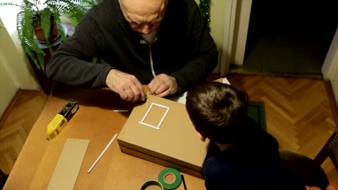 小男孩和他的祖父一起做纸箱
