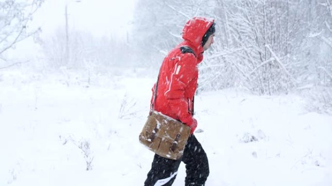 一位男性旅行者在大雪中漫步在树林中。