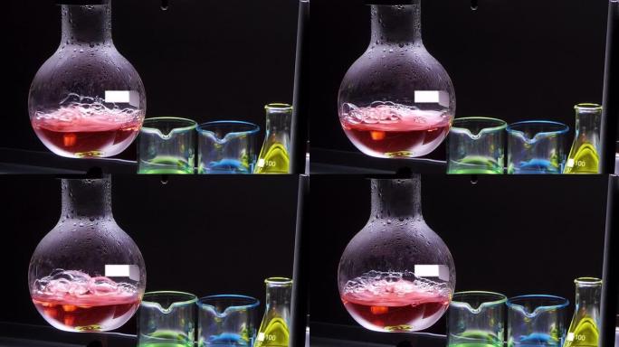 关闭酒精灯是用黑色背景的实验室玻璃器皿在烧瓶中沸腾的红色化学液体。实验室研究与开发