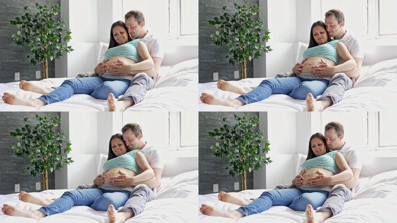 年轻的父母在床上期待一个小婴儿，为怀孕的夫妇浪漫的时刻