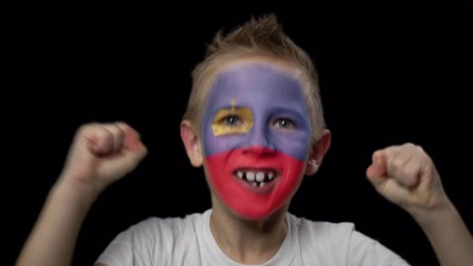 快乐的男孩为他最喜欢的列支敦士登队的胜利而高兴。脸上涂着民族色彩的孩子。