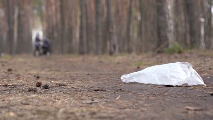森林地面上的玻璃纸袋。环境污染的概念