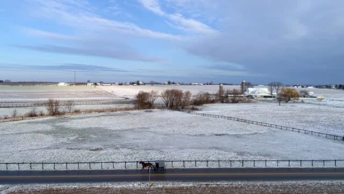 小雪落下后，阿米什乡村和马车在路上行驶的鸟瞰图