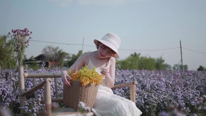 年轻的亚洲妇女爱抚玛格丽特的花朵与日落