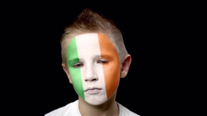 爱尔兰足球队的伤心球迷。脸上涂着民族色彩的孩子。