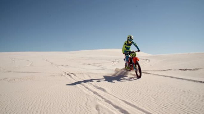 越野摩托车骑手在沙漠中表演独轮车