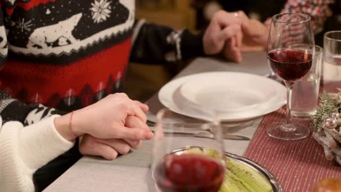 新年晚餐。家庭手牵食物前祈祷。手特写。