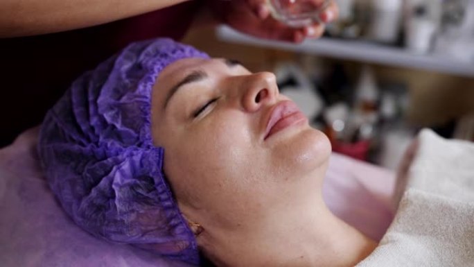 水疗沙龙的美容师用一刷特殊的油为客户提供面部护理。