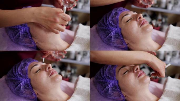 水疗沙龙的美容师用一刷特殊的油为客户提供面部护理。