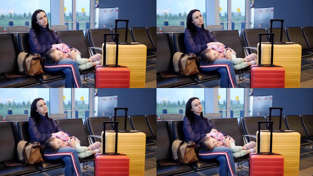 一位母亲抱着她的小女儿，在等待下一个航班时睡在机场航站楼的椅子上