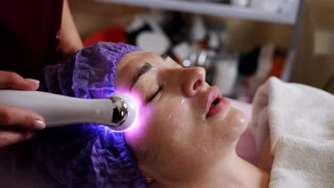 美容师用微晶换肤装置对躺在水疗中心的年轻女子进行面部去角质