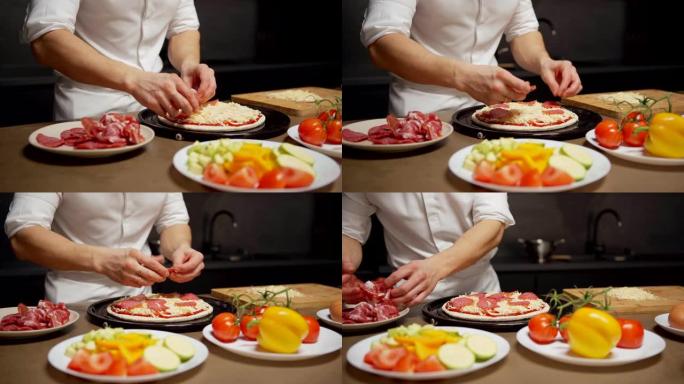 追踪无法识别的厨师将萨拉米或意大利辣香肠切片放在未完成的披萨上的特写镜头，站在餐厅厨房的桌子上，上面