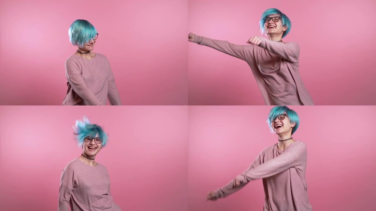 蓝色头发不寻常的女人在粉红色背景下在工作室里玩得开心，微笑，跳舞的模因时尚社交网络跳舞。音乐，舞蹈概