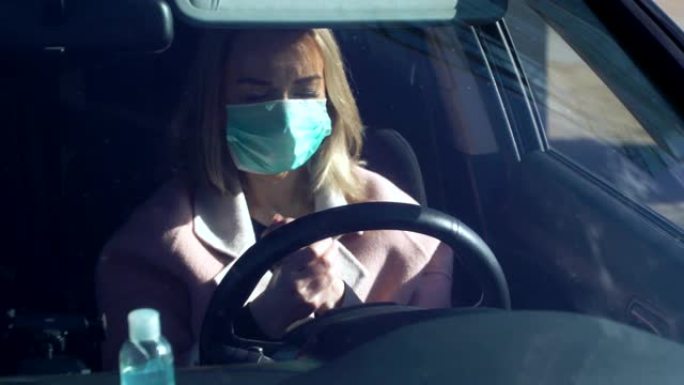戴着保护性无菌医用口罩的年轻女子在汽车上使用洗手液