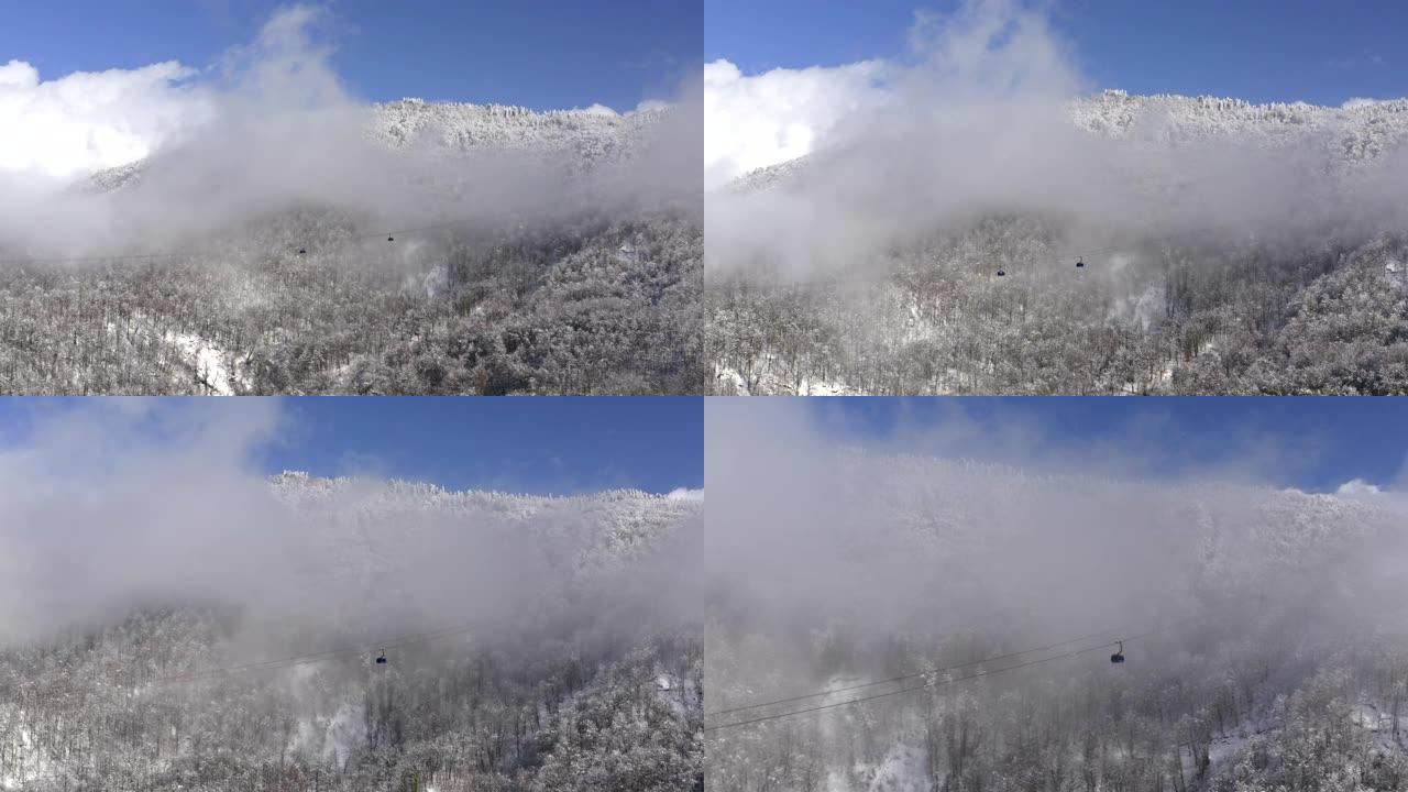 冬季度假胜地无人驾驶滑雪缆车穿越云层的惊人鸟瞰图。索道上的滑雪电梯运送滑雪场的人。蓝天景观上的无人机