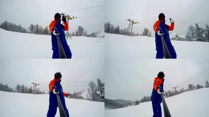 滑雪者做出手指向上的手势，开始从山上下降。带自拍杆的前视图。