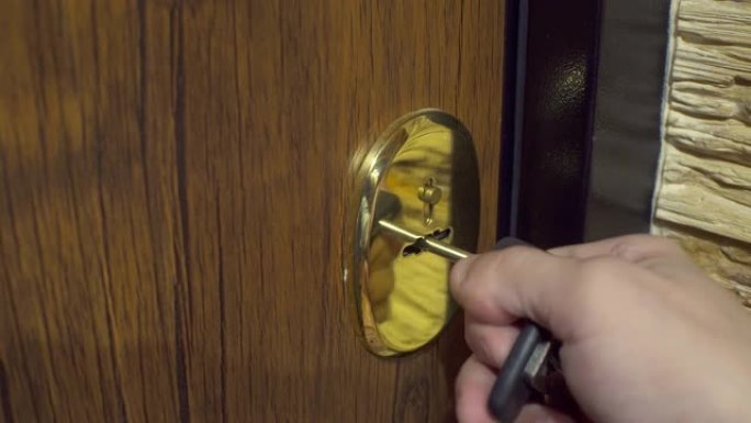 一个人的手将钥匙插入钥匙孔，然后打开和关闭门。特写。