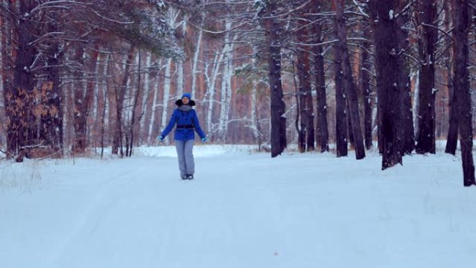 漂亮女孩走在冬天的森林里，沿着小路走，微笑着。森林中的冬季景观。