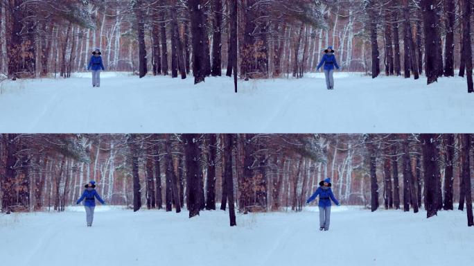漂亮女孩走在冬天的森林里，沿着小路走，微笑着。森林中的冬季景观。