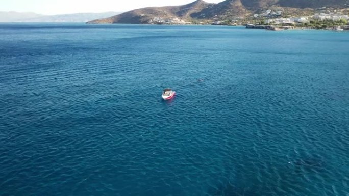 在深蓝色的海洋中飞驰的摩托艇的鸟瞰图。希腊克里特岛斯宾纳隆加岛