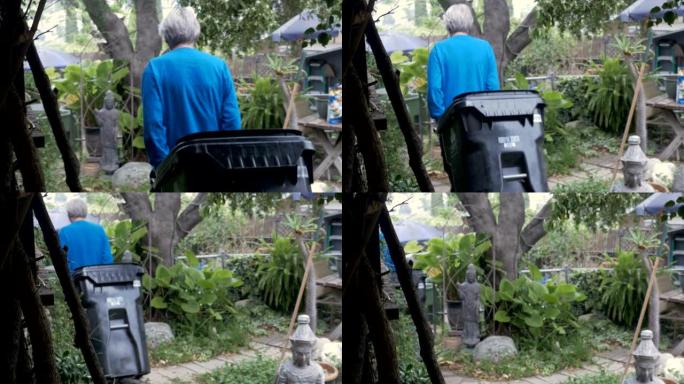 一位活跃的老年人将一个空的垃圾桶放到他的院子里
