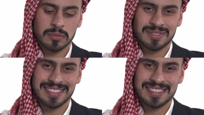 聚焦严肃的阿拉伯男子看着相机的特写。模特开始微笑。喜忧参半。孤立，白色背景