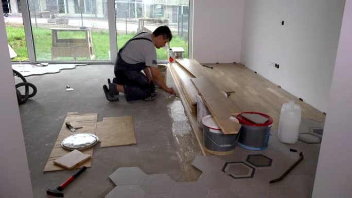 熟练工人在地板上用抹刀涂胶以铺设地板