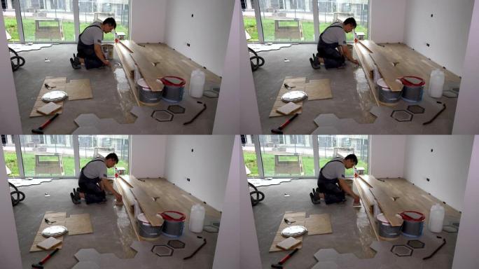 熟练工人在地板上用抹刀涂胶以铺设地板