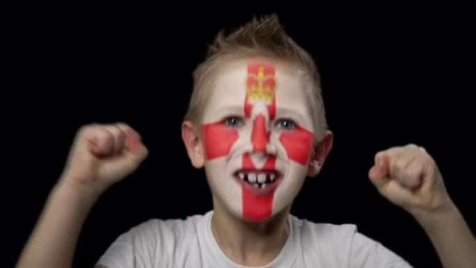 快乐男孩为他最喜欢的北爱尔兰队的胜利而高兴。脸上涂着民族色彩的孩子。