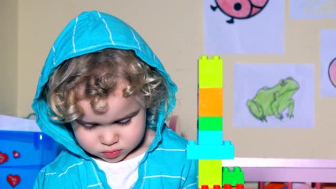 小女孩用连接塑料块砖块建造塔