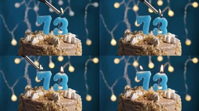 蓝色背景上有73号蜡烛的生日蛋糕。蜡烛着火了。慢动作和特写视图