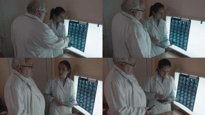 两名外科医生讨论头部的ct扫描和肩部的MRI扫描。神经外科医生团队在观察患者的断层摄影时谈论他们将要