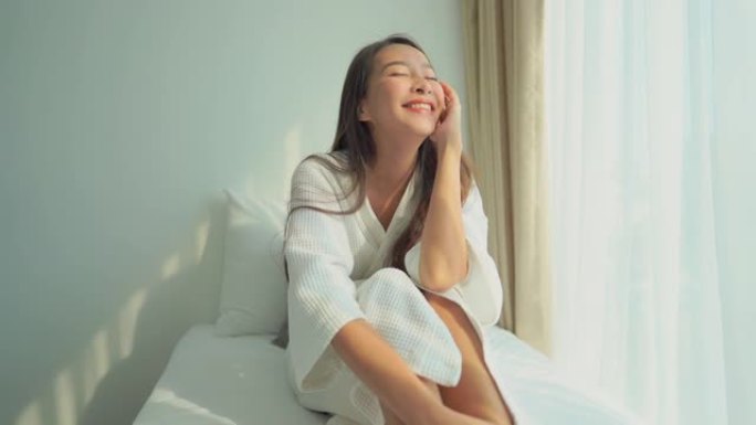 年轻的亚洲女性快乐的微笑在卧室的床上放松