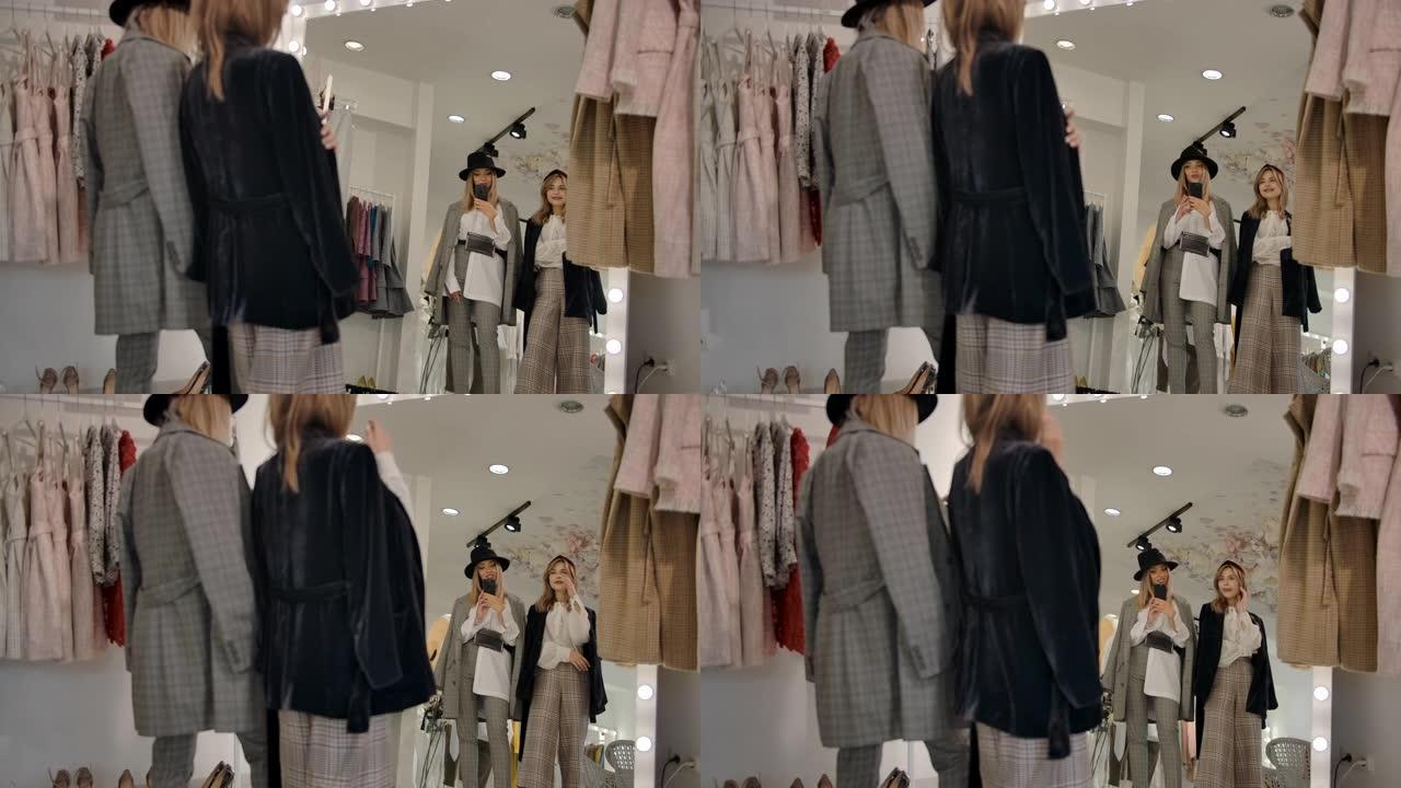 时尚快乐的年轻女性在试衣间对着现代精品店的大镜子自拍