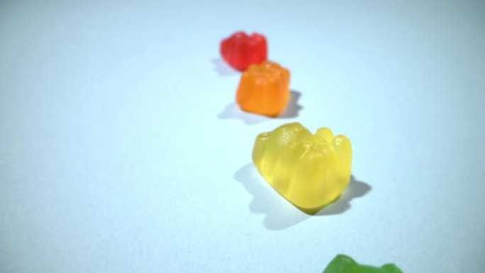 宏观特写广角滑动镜头含糖五颜六色美味甜软糖熊糖果堆在蓝色背景上