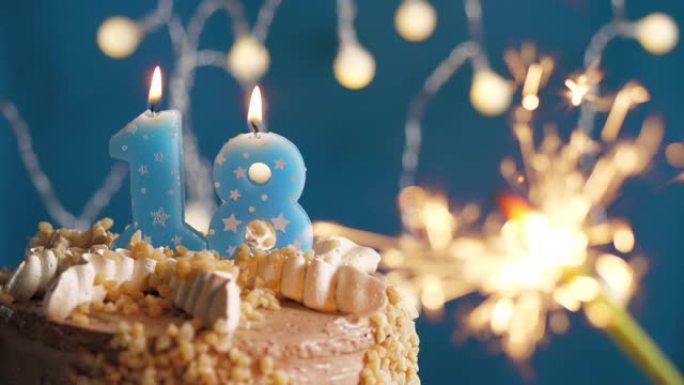 蓝色背景上有18个数字蜡烛和烟火的生日蛋糕。慢动作和特写视图